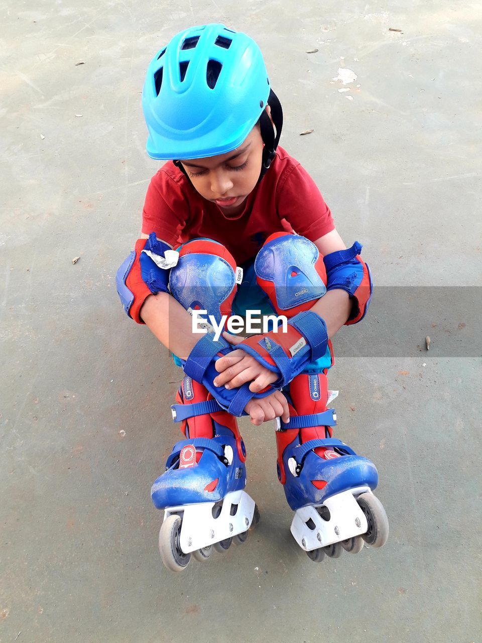 High angle view of sad boy with inline skates sitting at playground