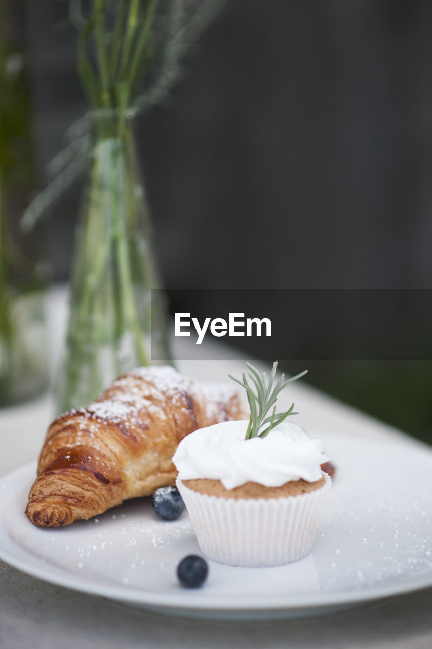 Close-up of cupcake with croissant on plate