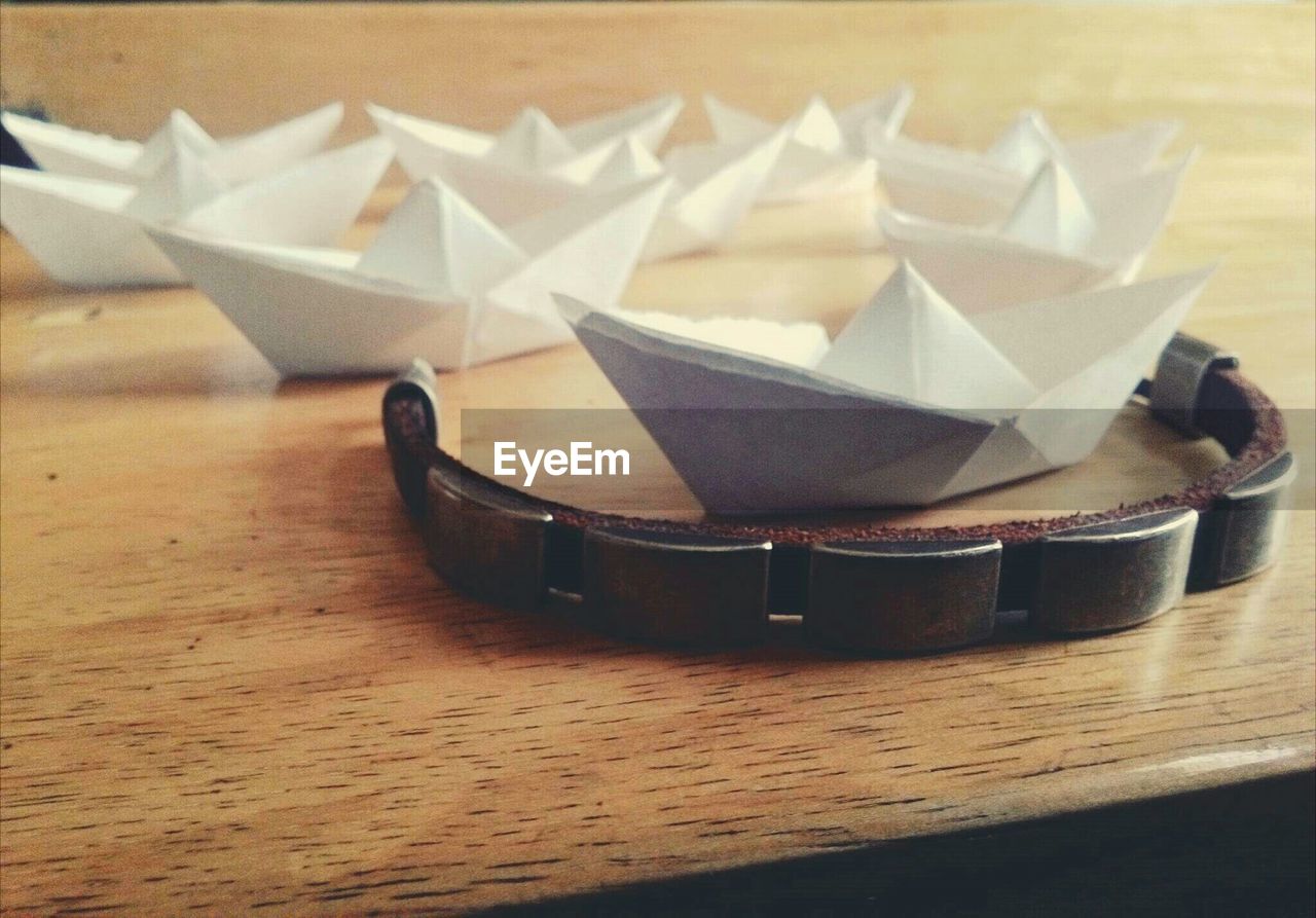 Paper boats and bracelet on wooden table