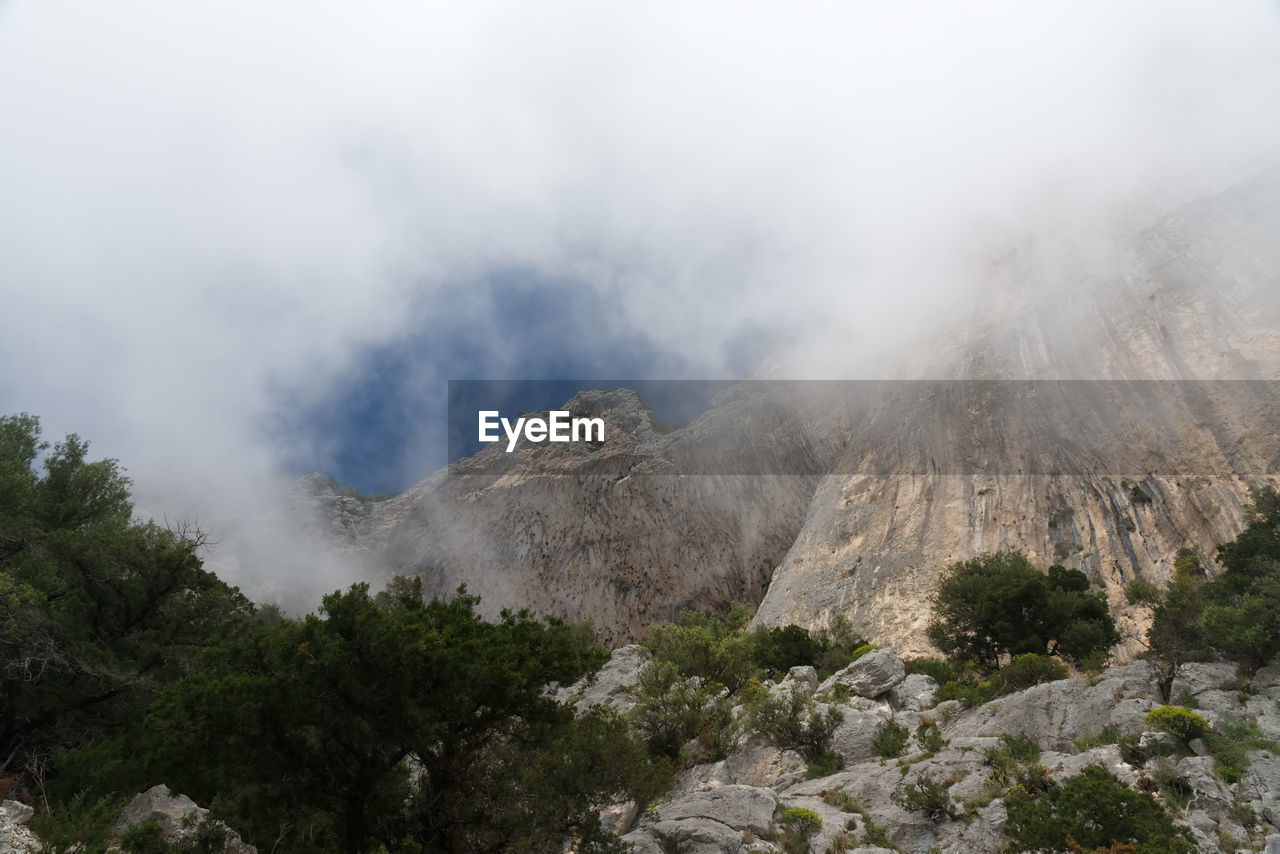 SCENIC VIEW OF SMOKE EMITTING FROM VOLCANIC MOUNTAIN AGAINST SKY
