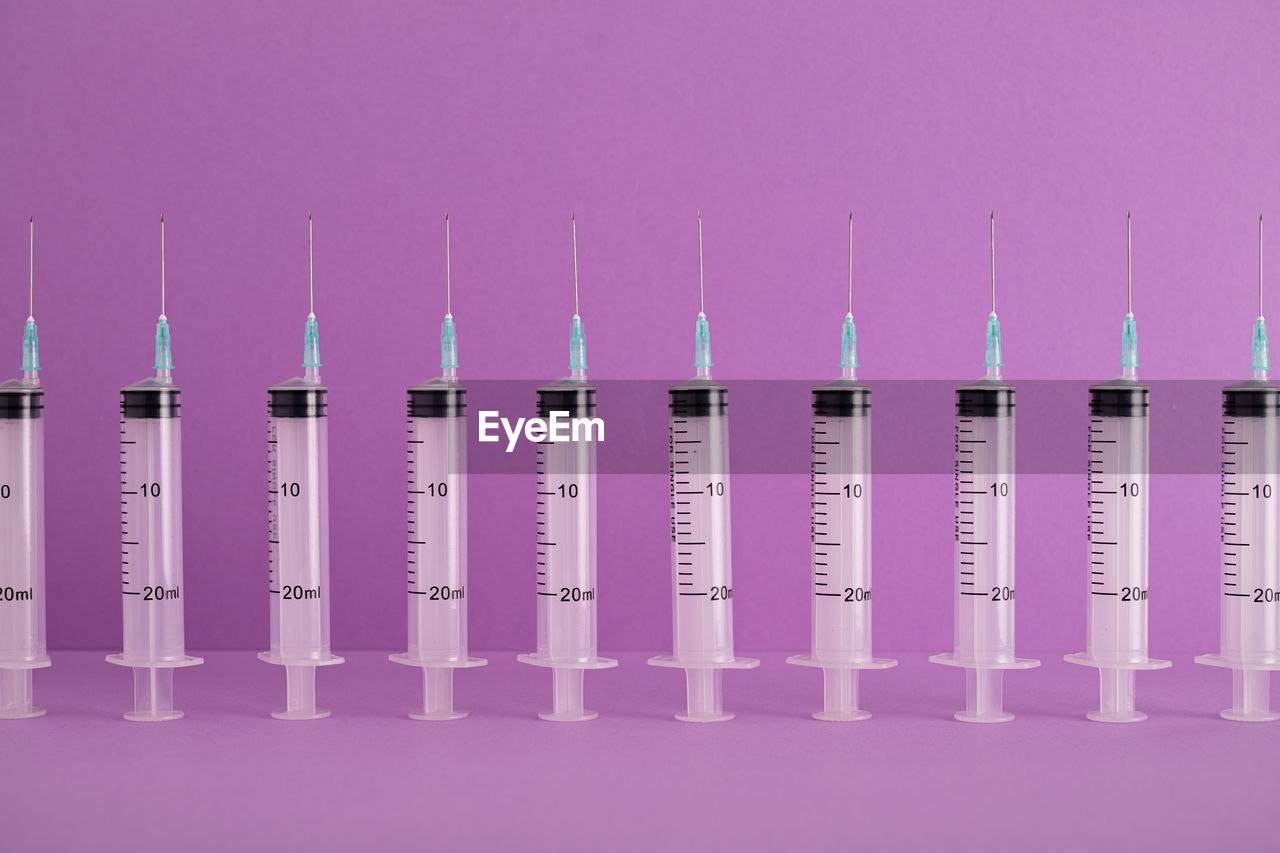 Row of syringes over purple background