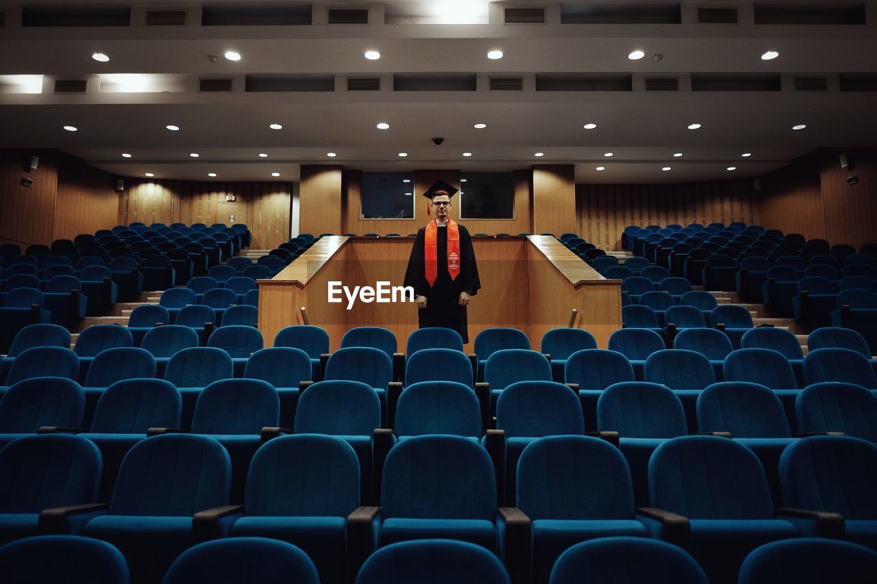 Man standing amidst chair in lecture hall