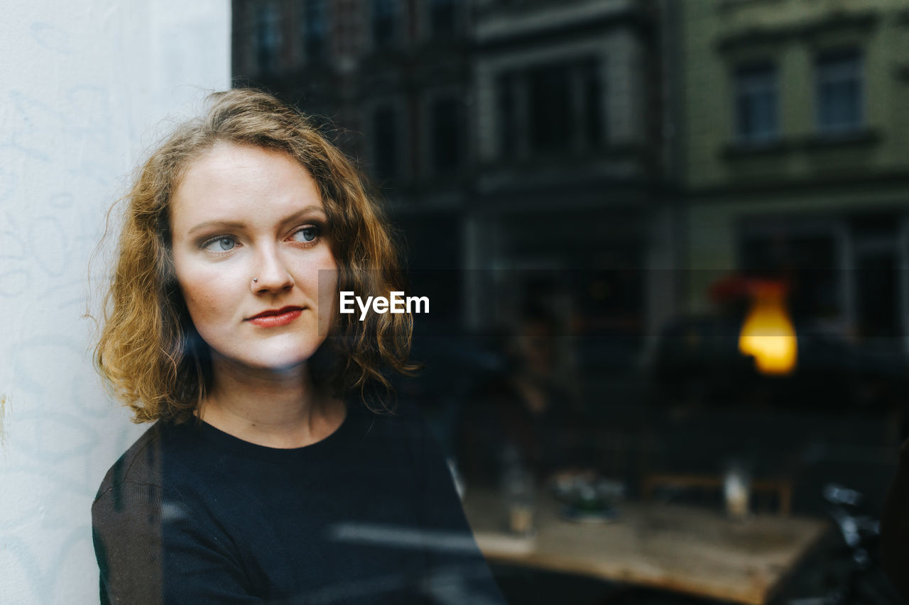 Thoughtful woman looking through window at cafe
