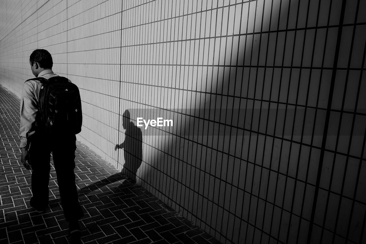 Rear view of a man walking by the wall