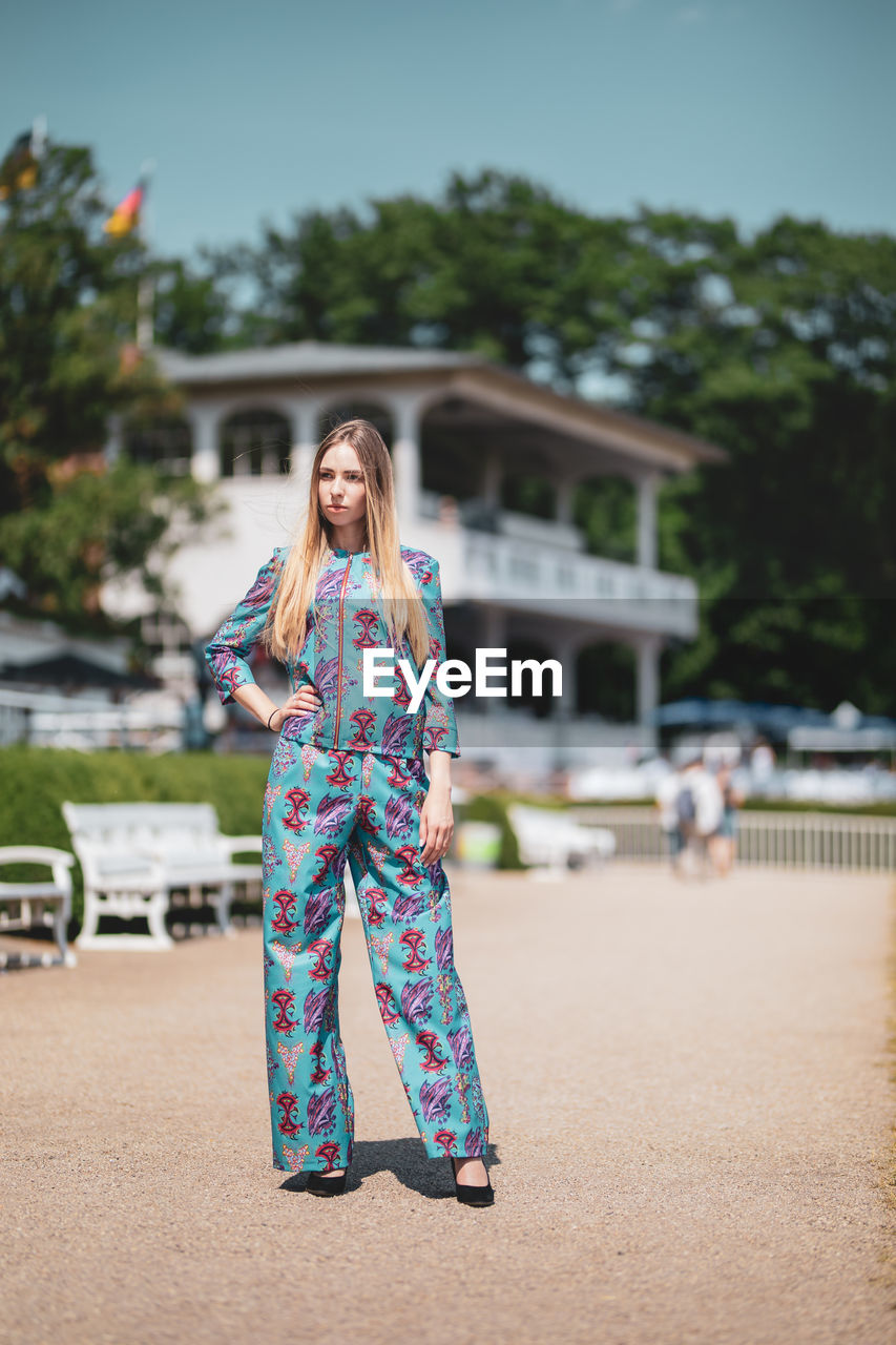 Female model standing on field against building