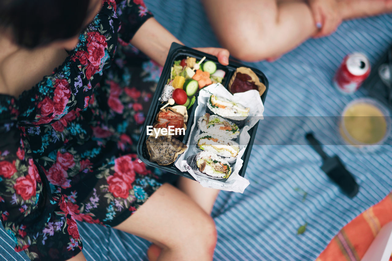 Cropped image of woman holding sushi in container