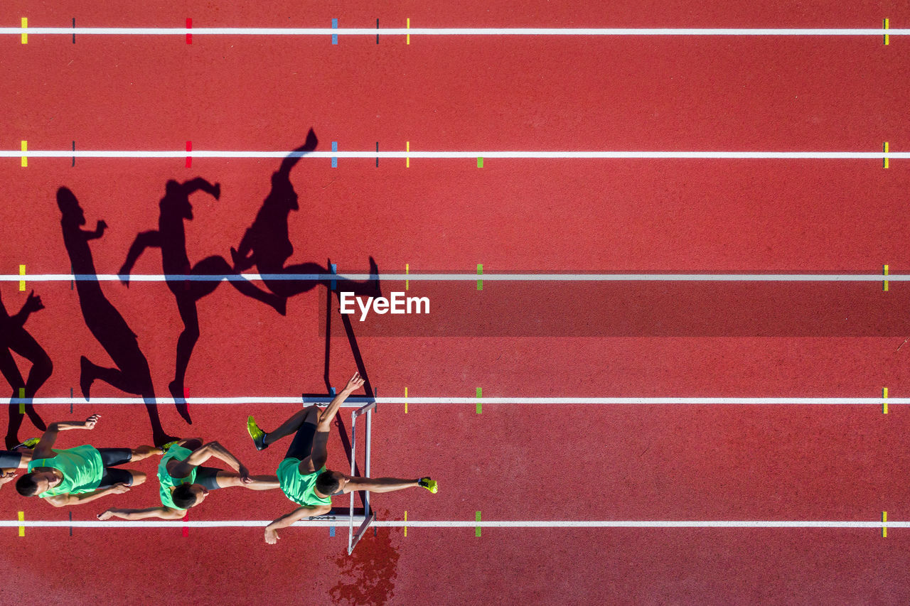 HIGH ANGLE VIEW OF TWO PEOPLE RUNNING ON RED WALL