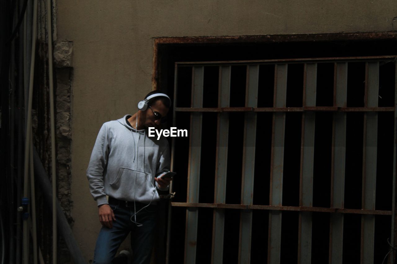 Man using phone while standing by wall