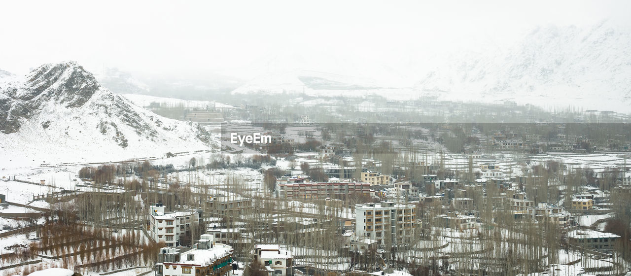 HIGH ANGLE VIEW OF TOWNSCAPE AND SNOWCAPPED MOUNTAIN