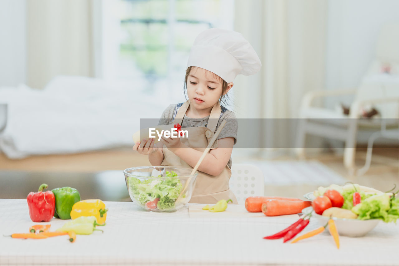 MIDSECTION OF GIRL HOLDING FOOD AT TABLE