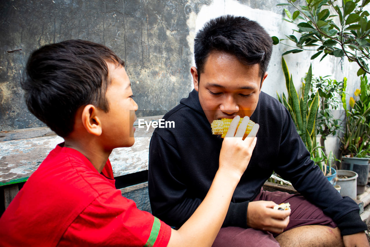 Boy feeding corn to brother