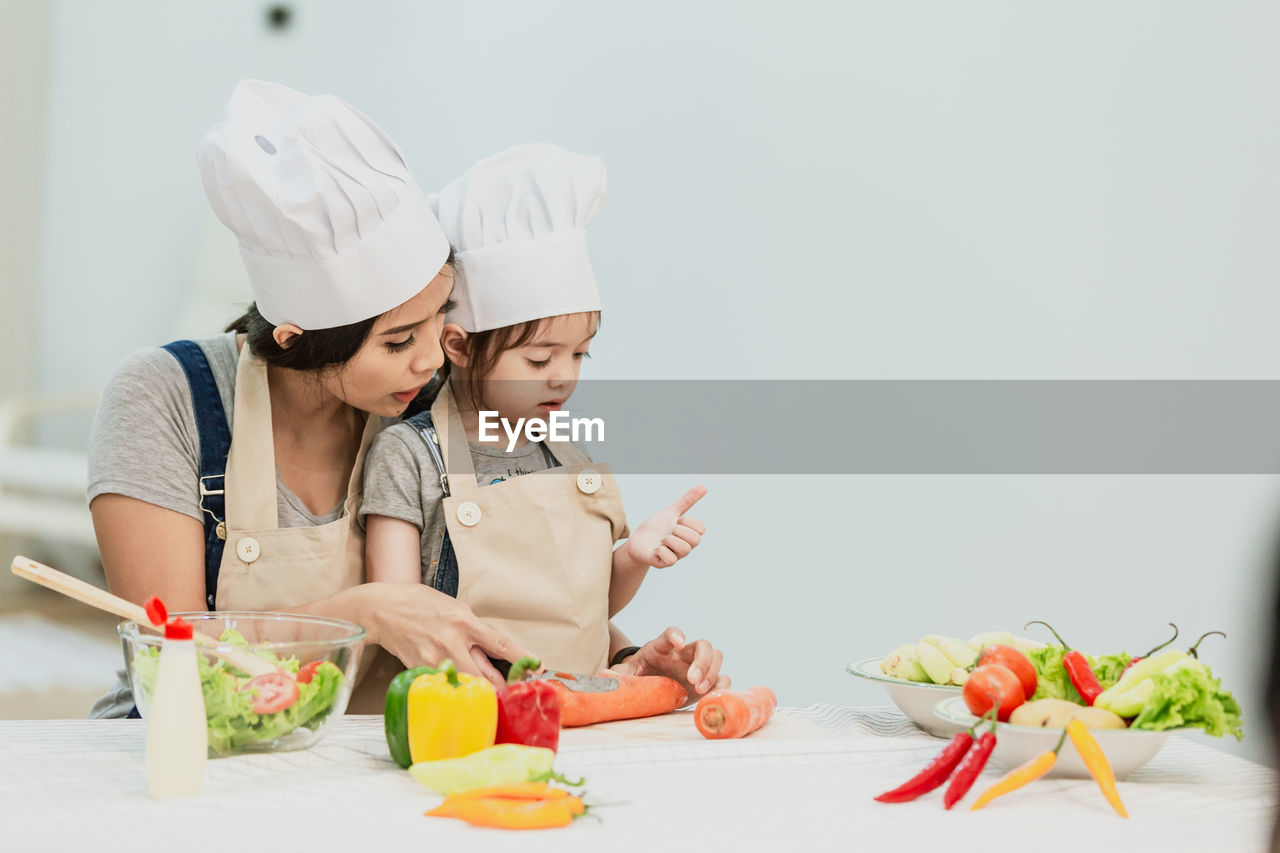 Mother and daughter preparing food on table