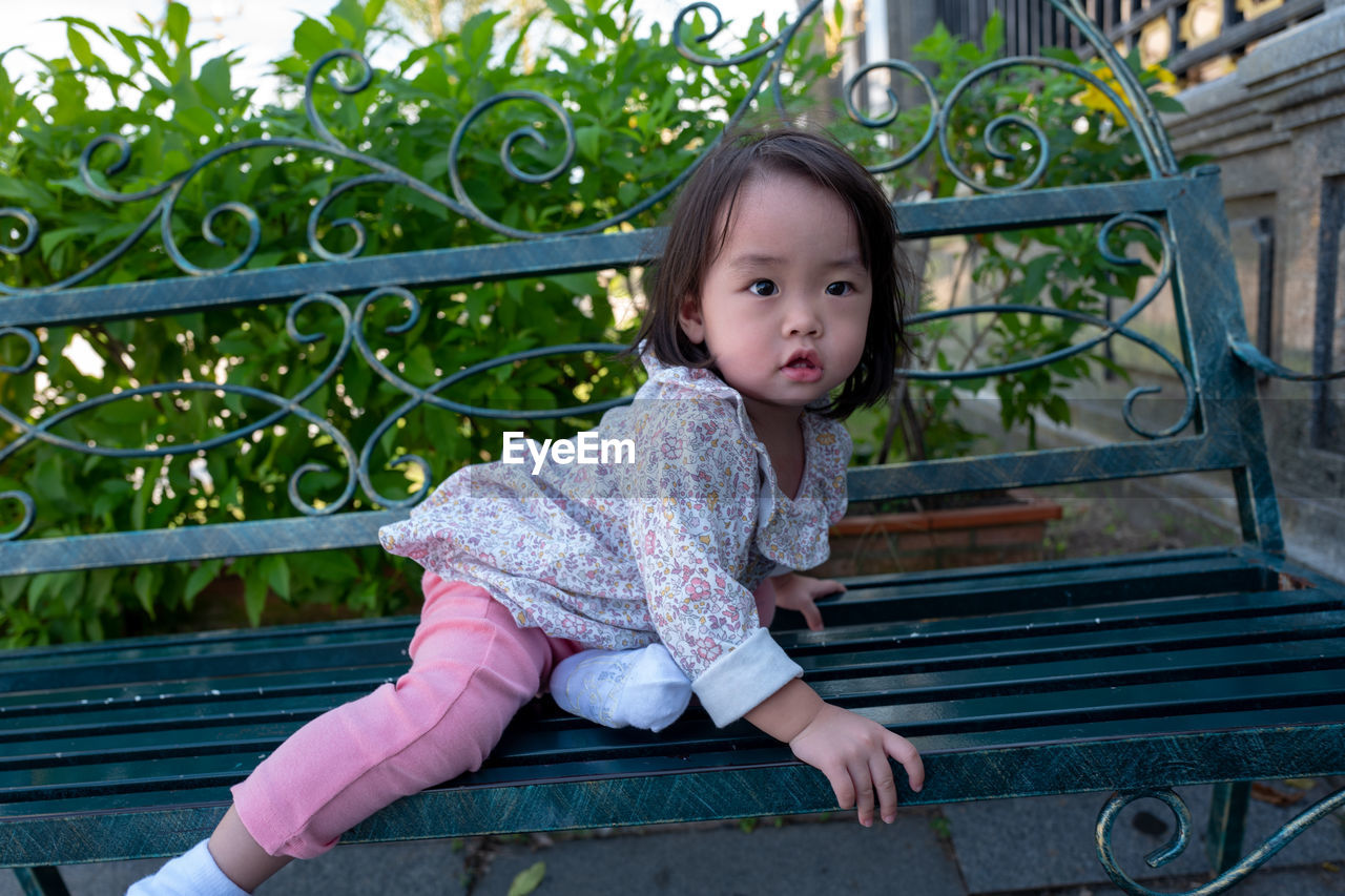 Cute Baby Girl Sitting On Bench In City On Eyeem