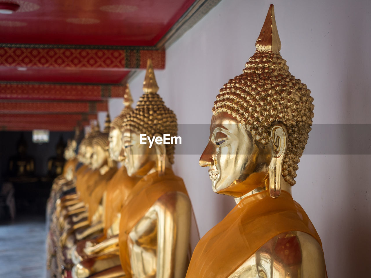 Row of golden buddha statues at wat pho temple, bangkok, thailand