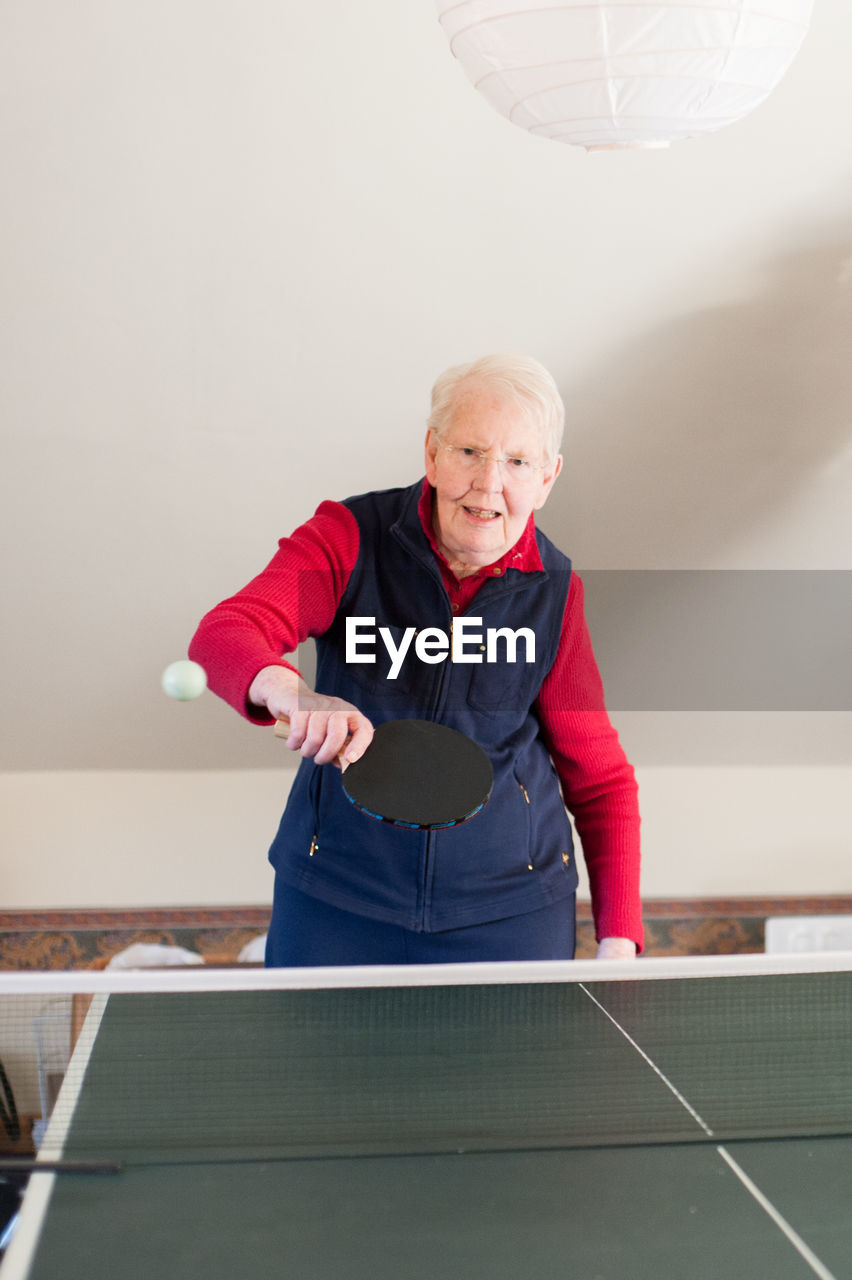 An elderly lady playing table tennis.