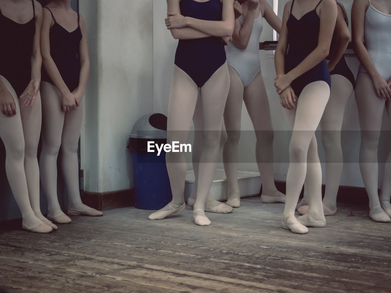 Low section of ballet dancers standing on wooden floor