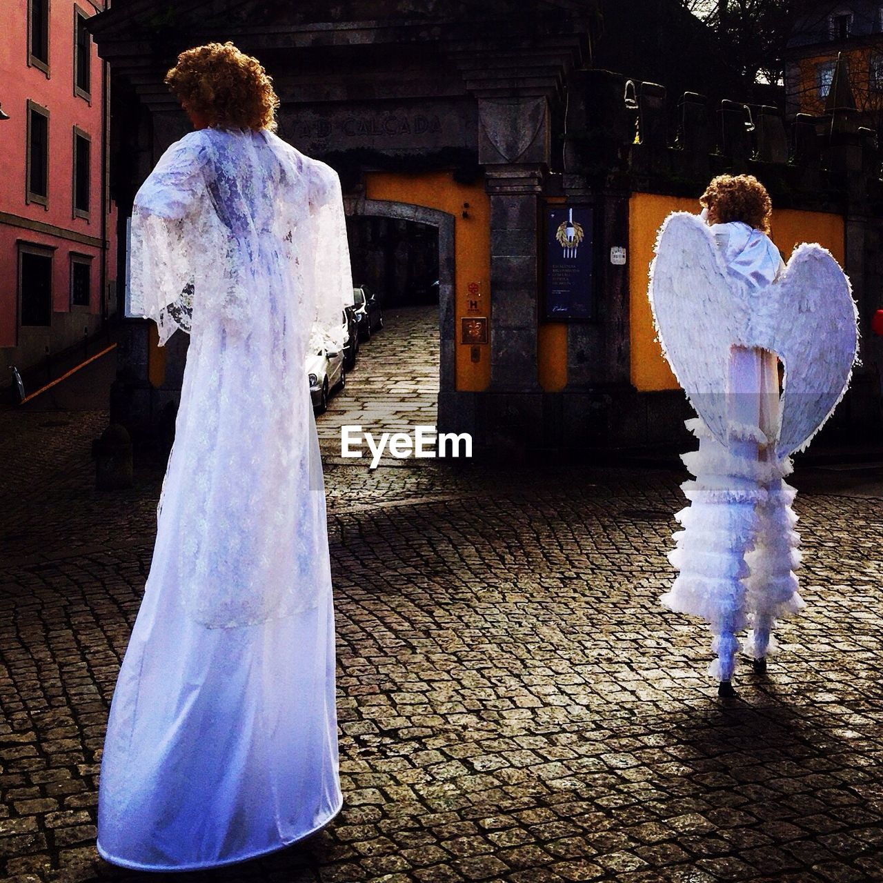 Rear view of woman and girl in angel costume standing on street