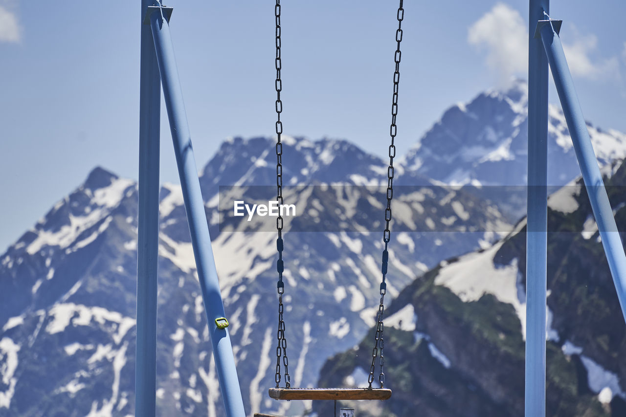 CLOSE-UP OF SWING AGAINST SNOWCAPPED MOUNTAIN