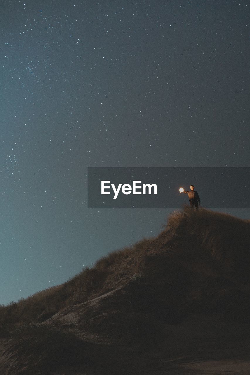 Low angle view of man on mountain against sky at night