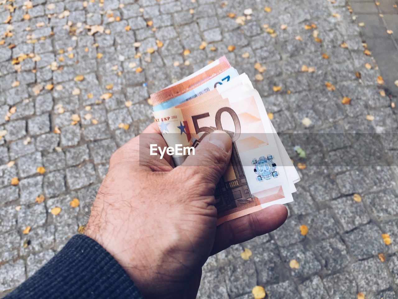 Cropped hand holding paper currency over street