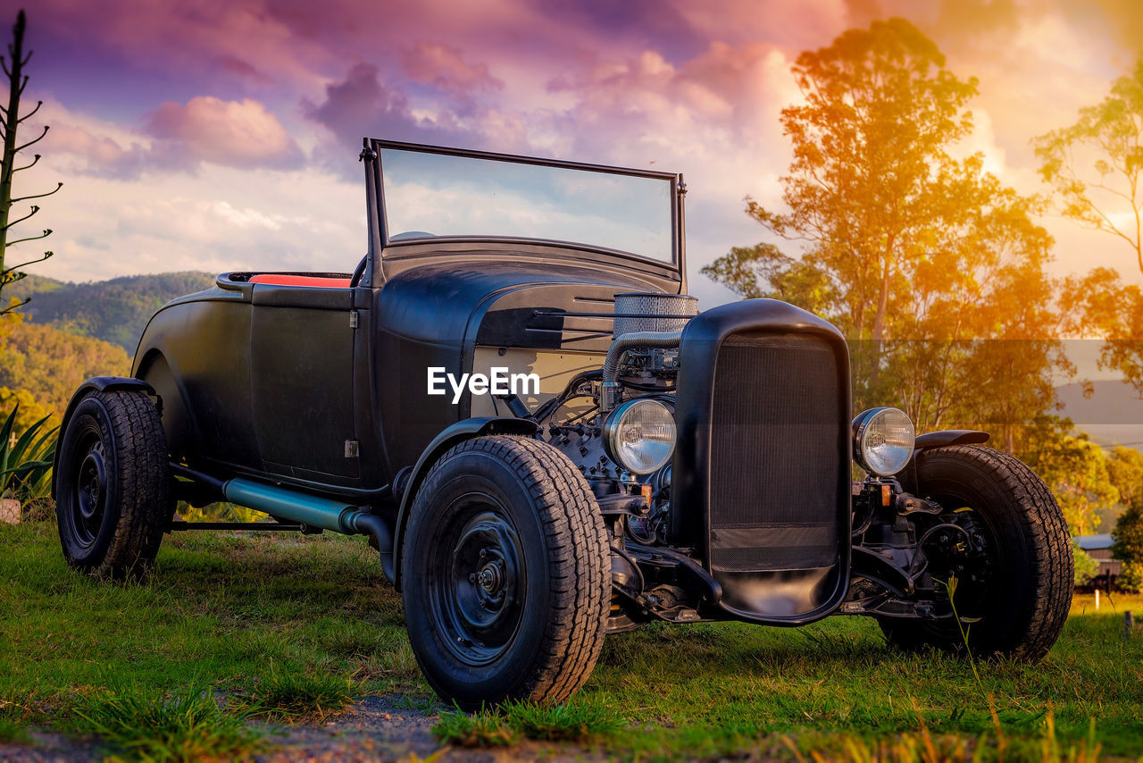 Vintage car parked at grassy area against cloudy sky