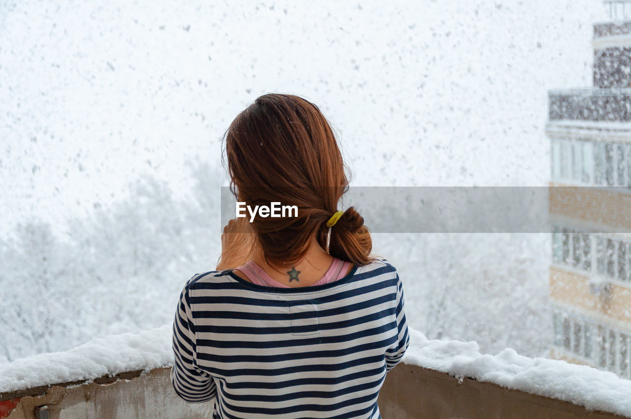 Rear view of woman looking at snow outdoors