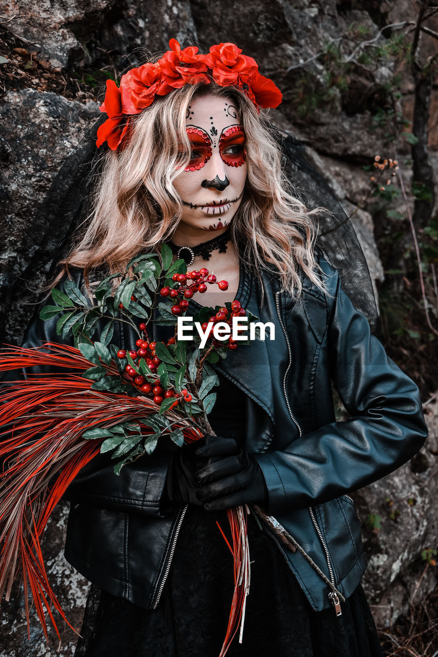 Closeup portrait of calavera catrina. young woman with sugar skull makeup and red flowers. dia 