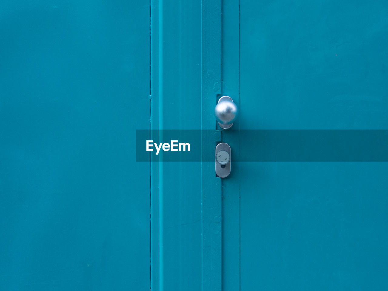 Silver doorknob on closed blue metallic door