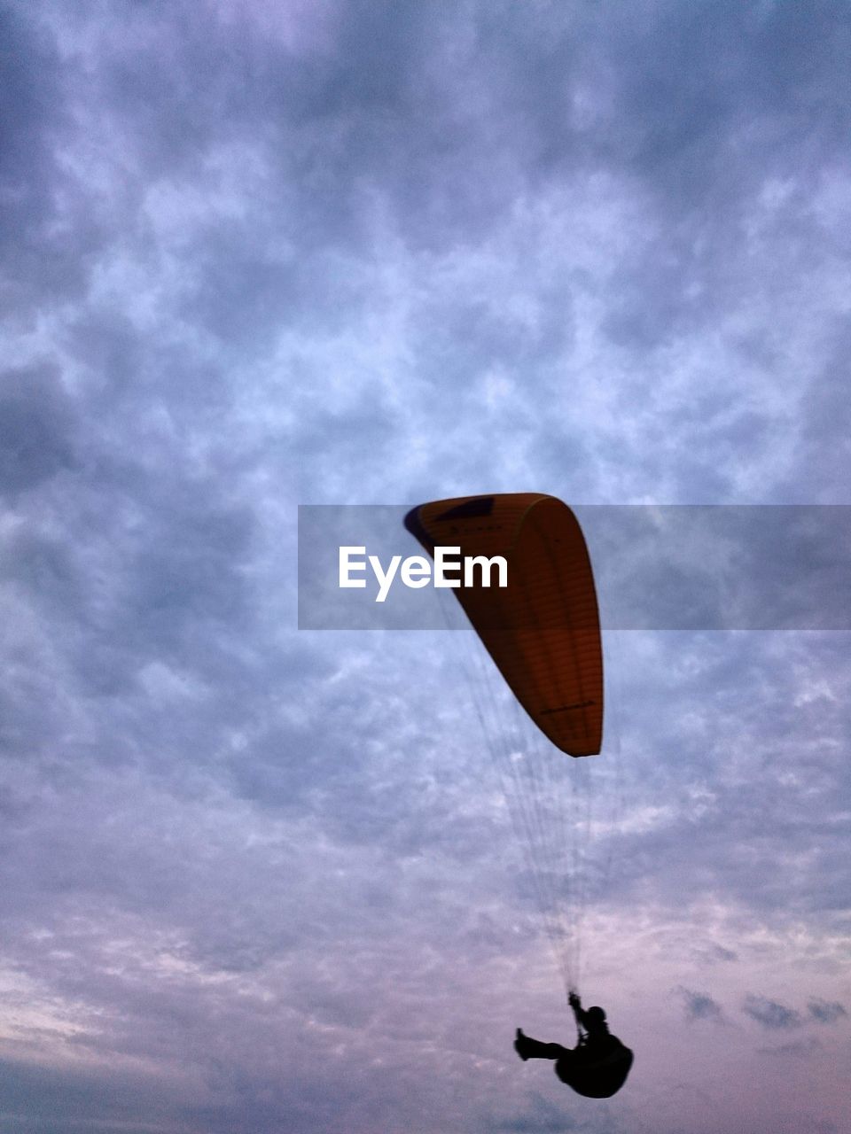 Person paragliding against cloudy sky