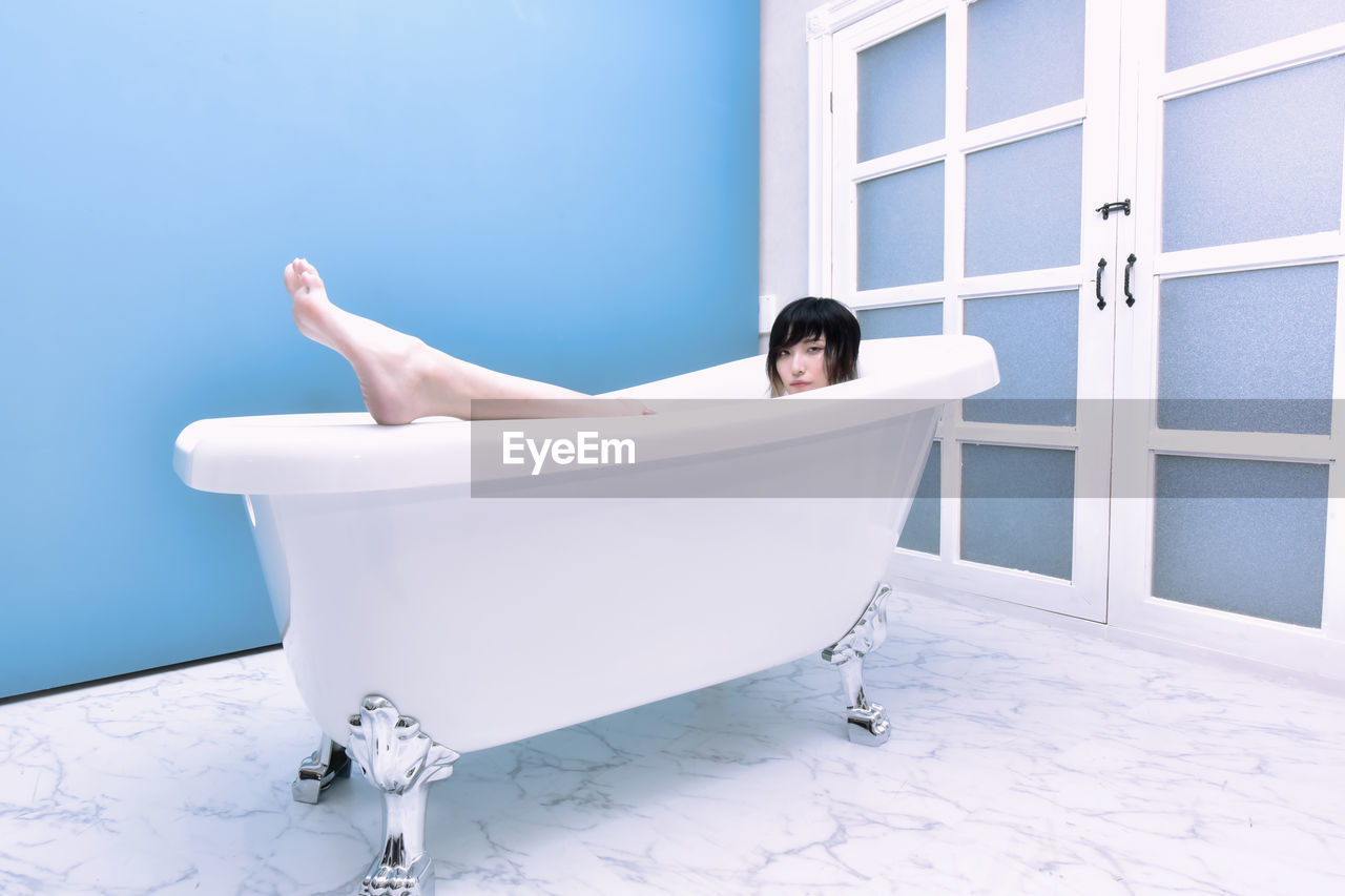 Young woman lying down in bathroom