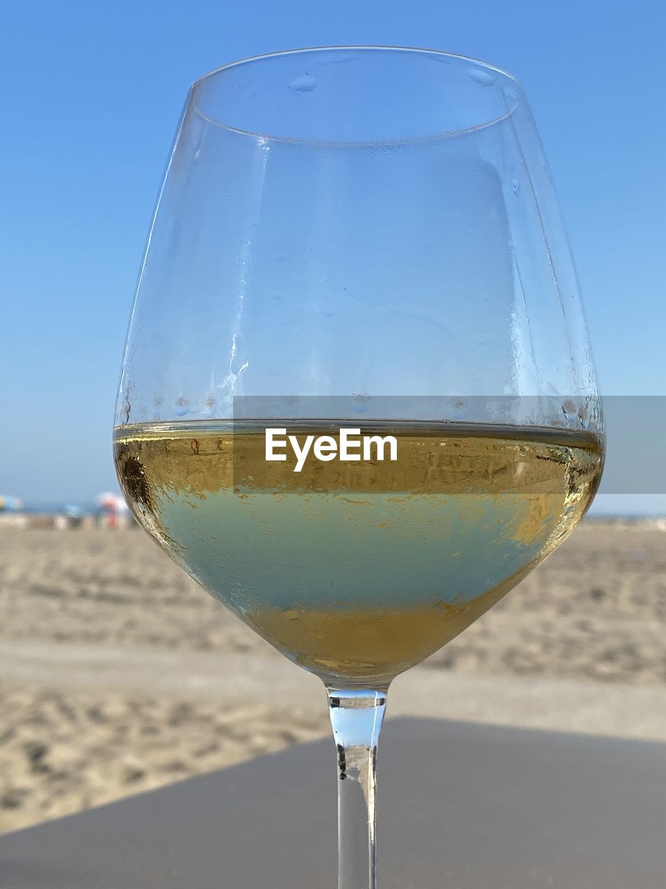 CLOSE-UP OF WINE GLASS ON SAND