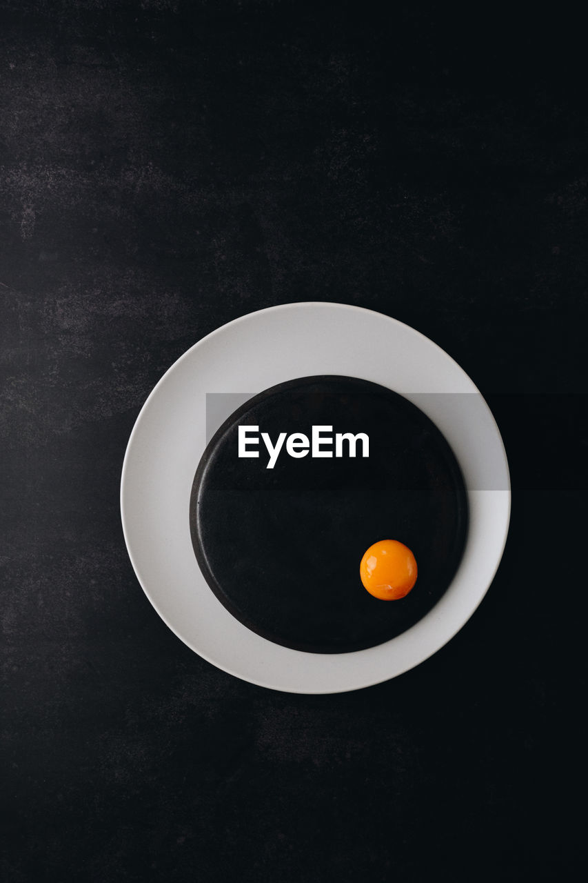 Idea of rounded black and white plates with egg yolk. minimal contemporary art idea or inspiration.