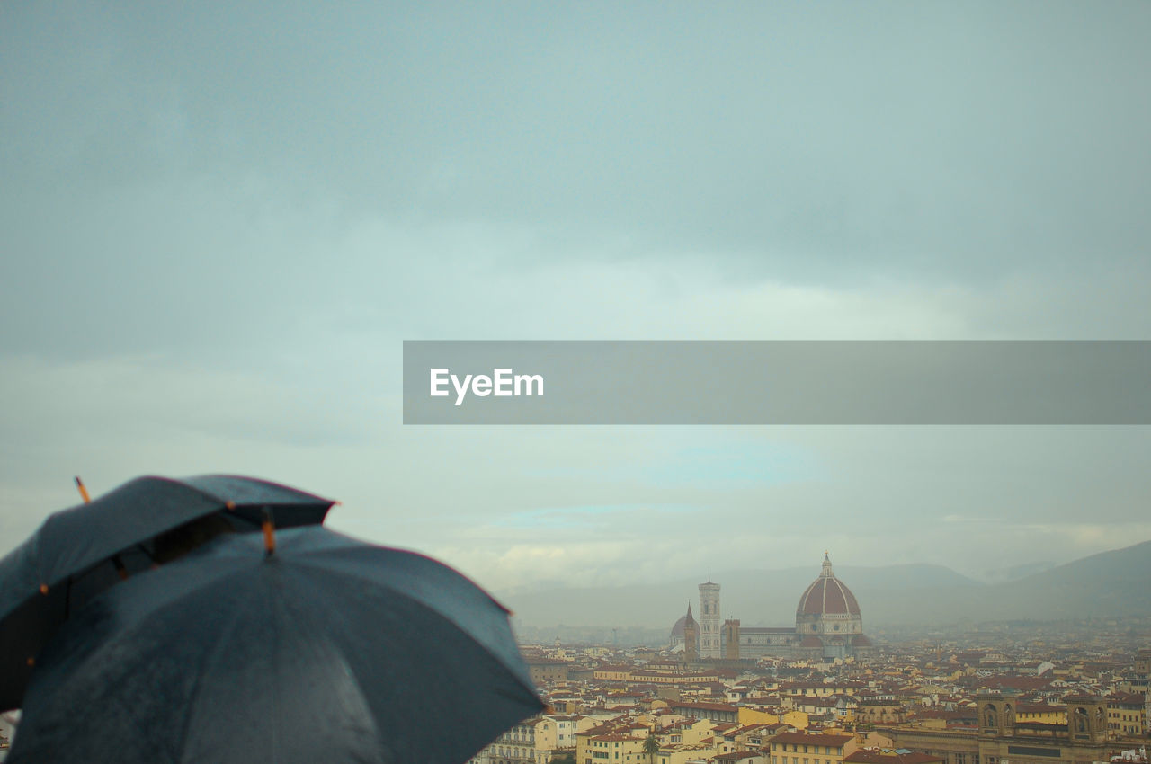 Umbrellas during rainy season with florence cathedral in background against sky