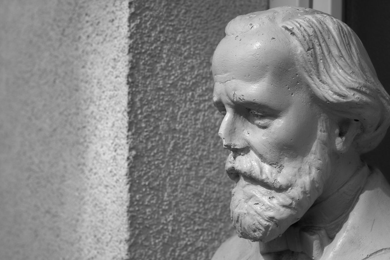 CLOSE-UP OF STATUE OF MAN AGAINST WALL