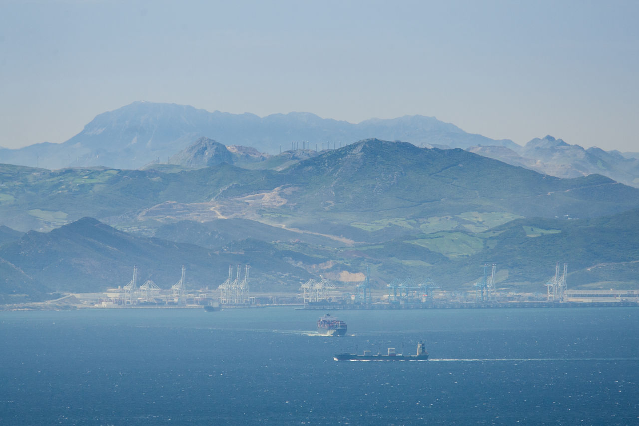 SCENIC VIEW OF SEA AGAINST MOUNTAINS
