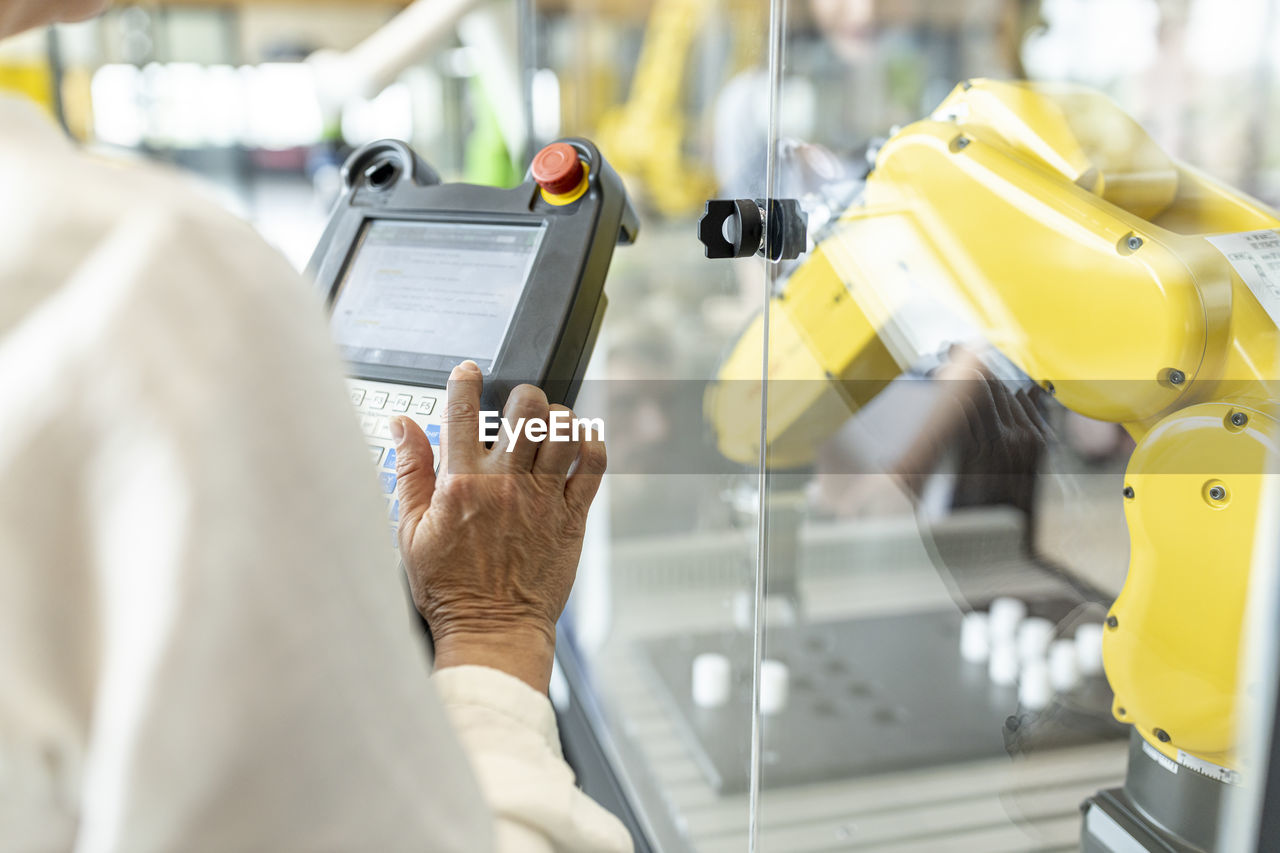 Woman in factory using control of industrial robot