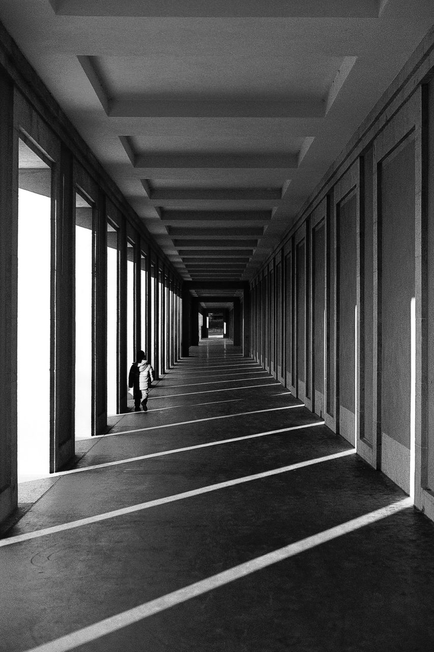 Full length rear view of person walking on corridor