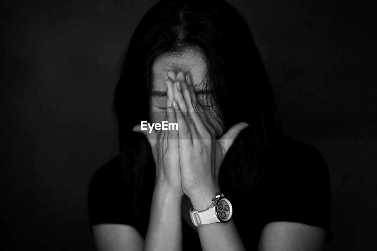 Close-up of woman crying against black background