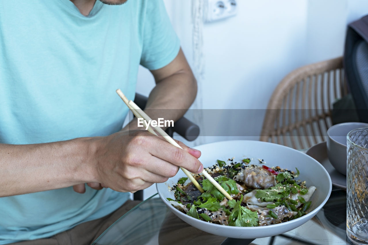 MIDSECTION OF MAN HAVING FOOD IN BOWL