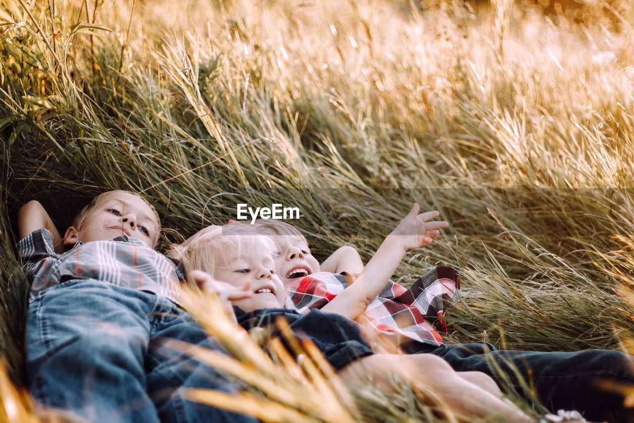 Close-up of siblings lying on grass