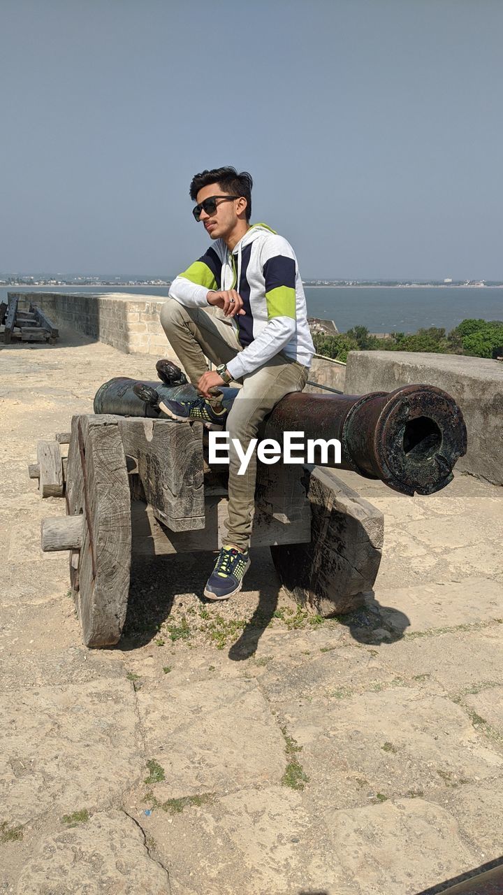 Man sitting in sunglasses against clear sky