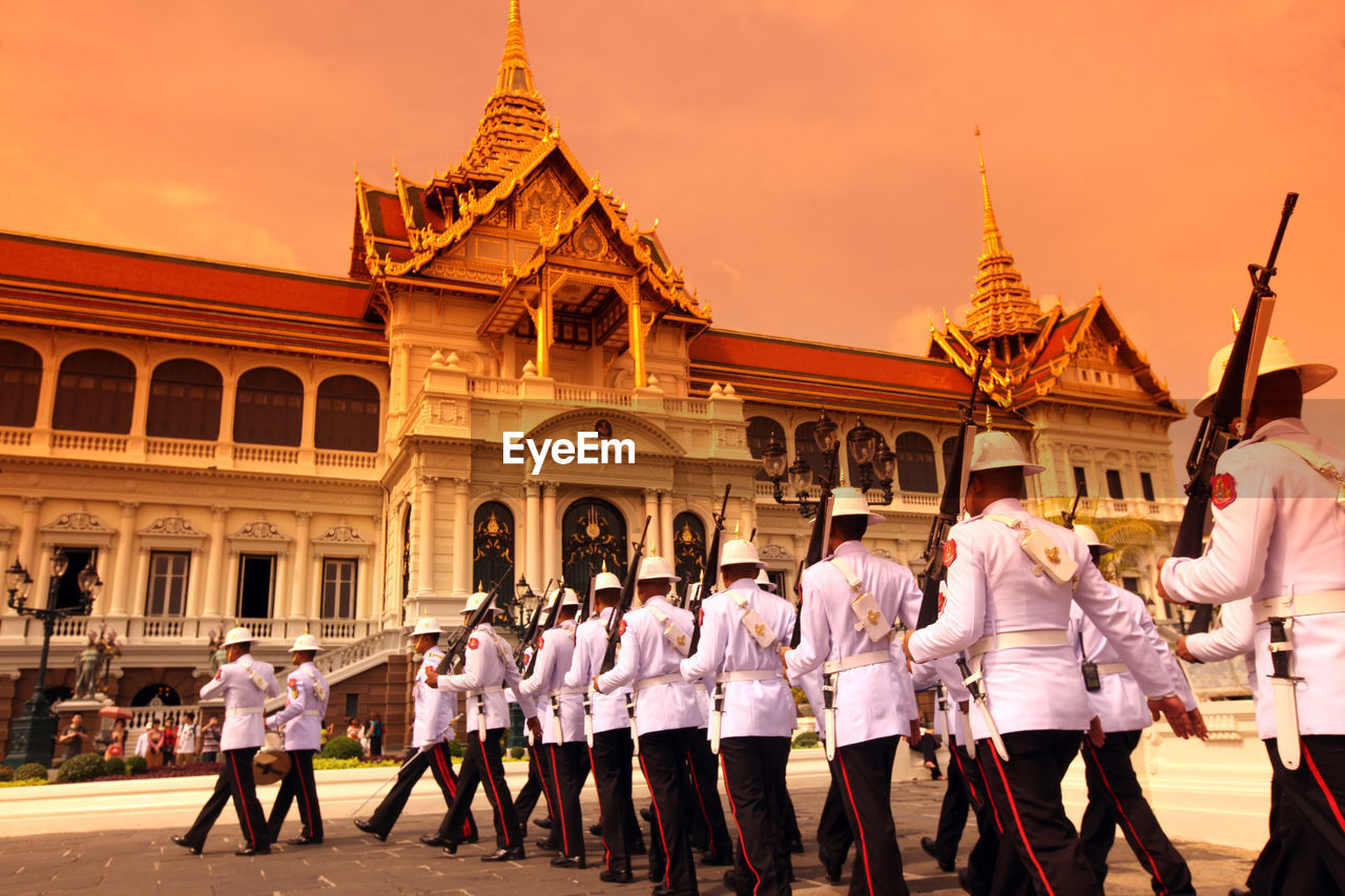 Army soldiers marching by historic building during sunset