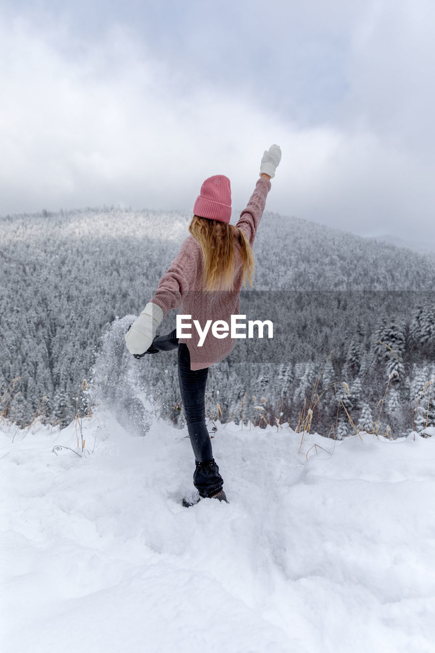 Woman standing on snow covered land against sky