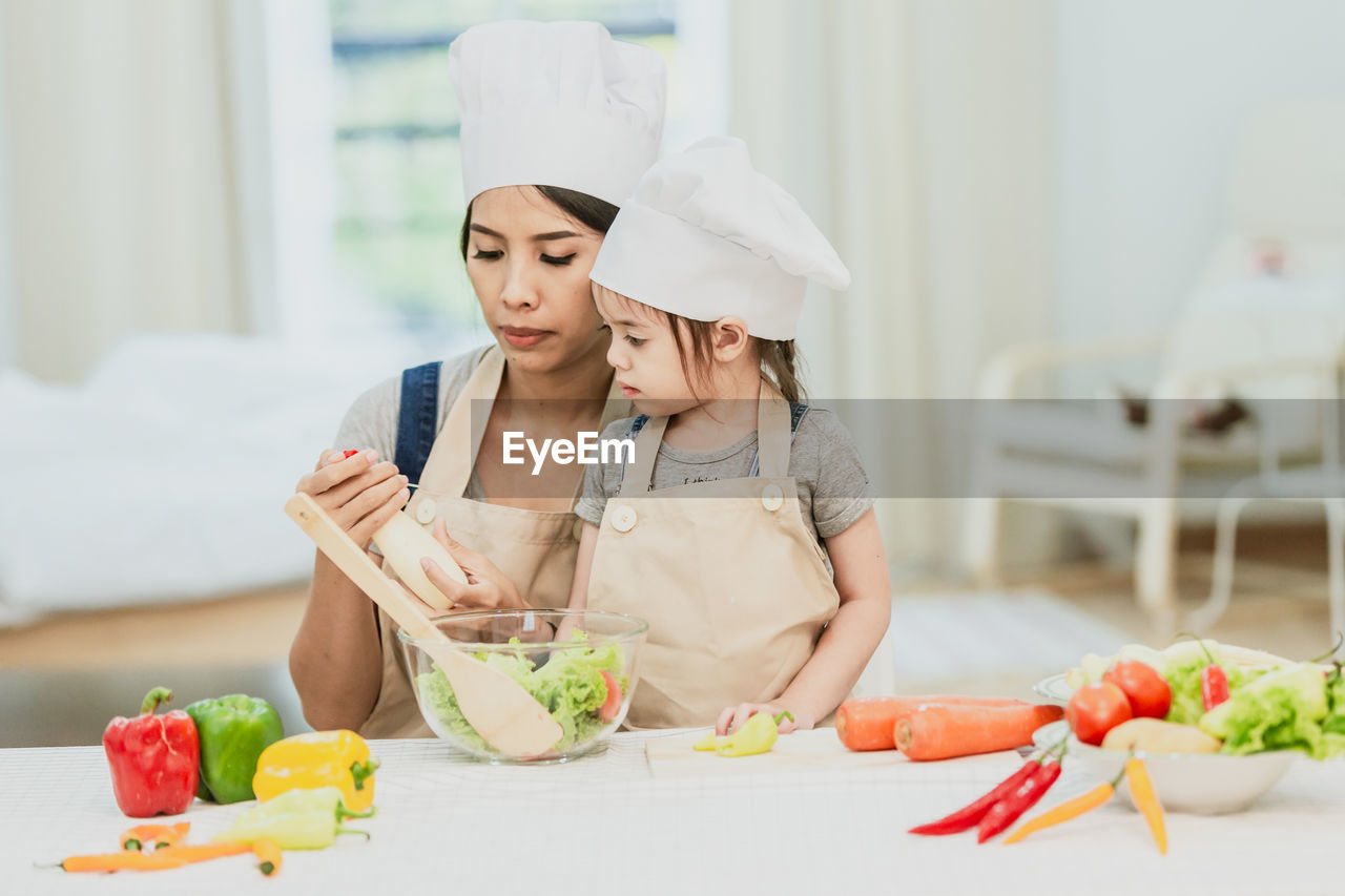 Mother and daughter preparing food on table