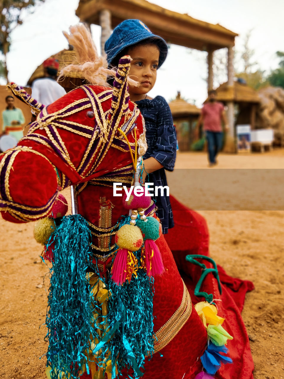 Girl looking away while sitting on artificial decorated horse