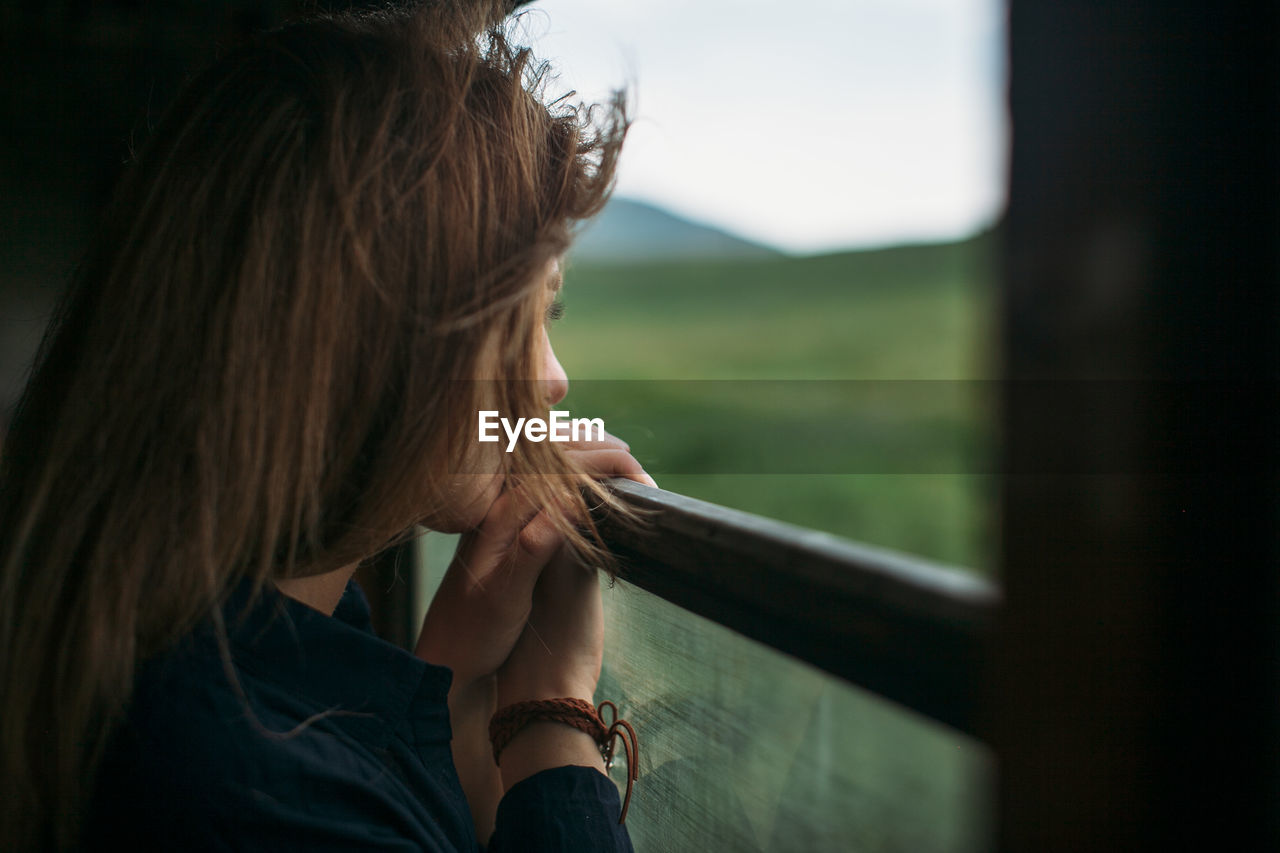 Close-up of woman looking though train window