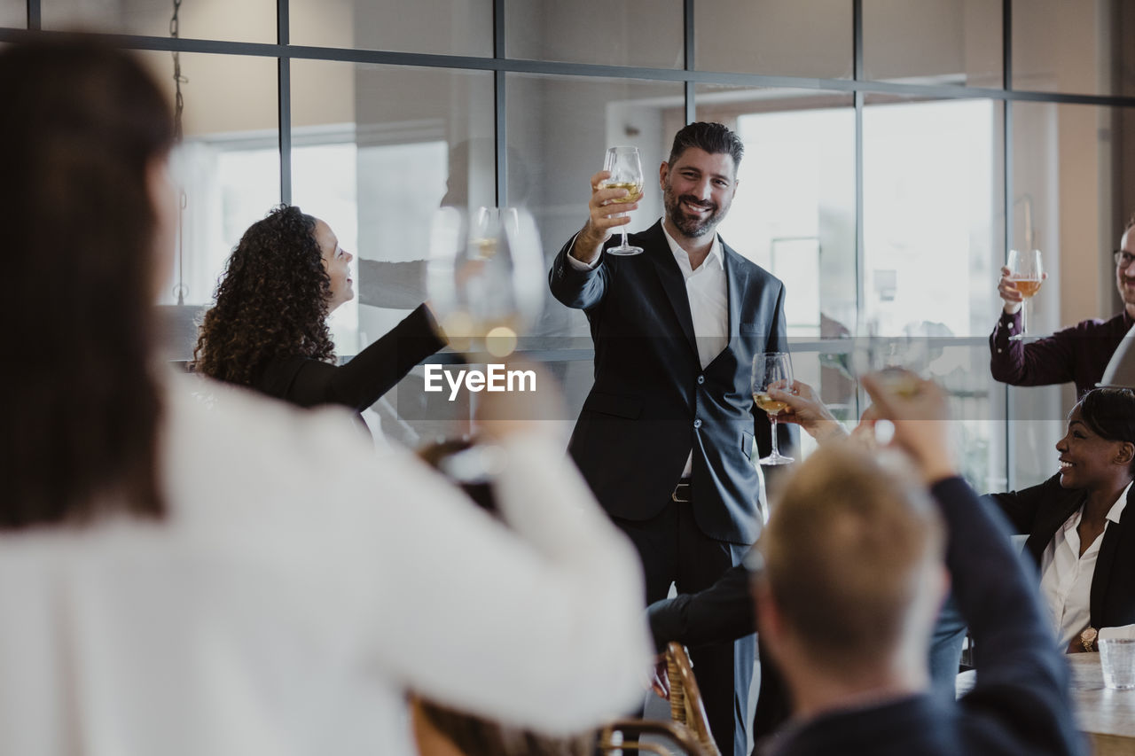 Cheerful male and female toasting wineglasses during office party