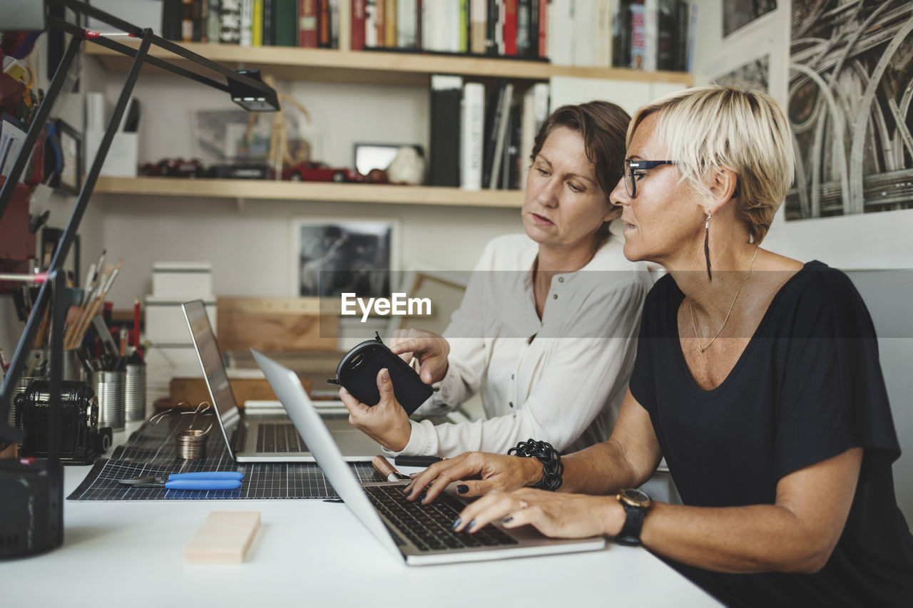 Female designers discussing over solar product at home office