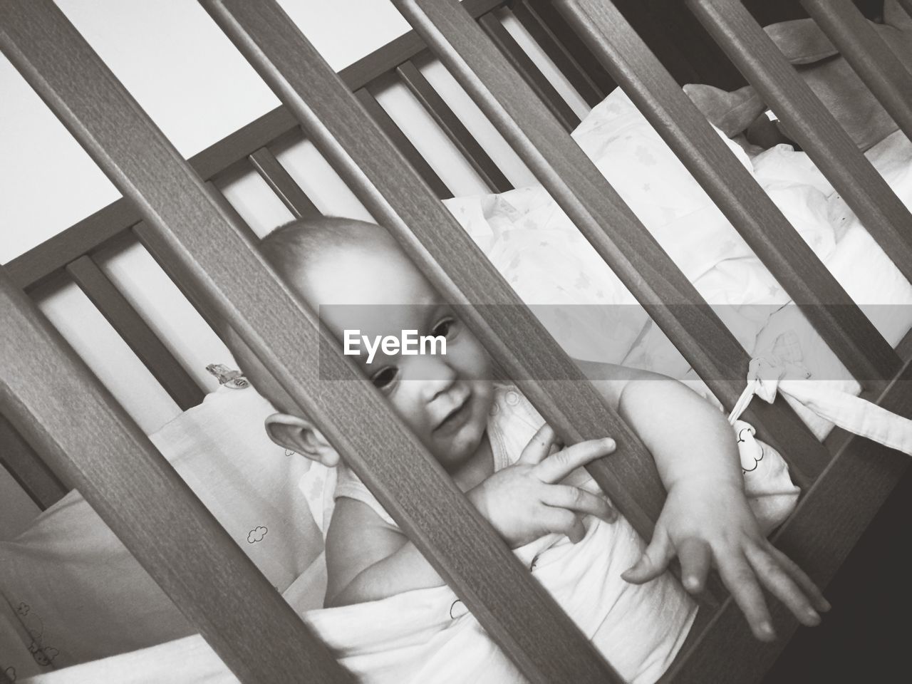 Close-up of baby boy looking through railing while lying in crib
