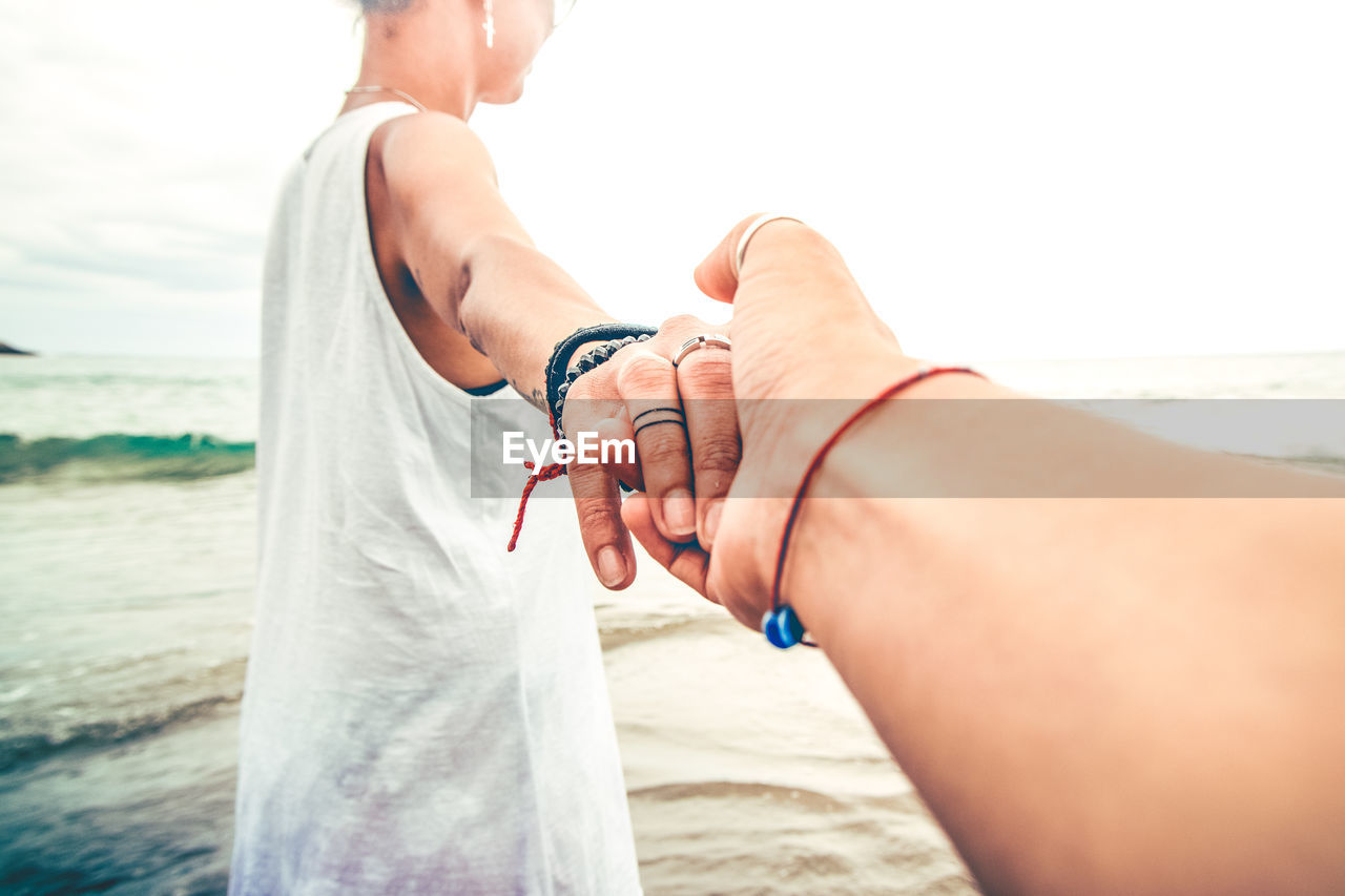 Woman holding boyfriend hand at sea shore